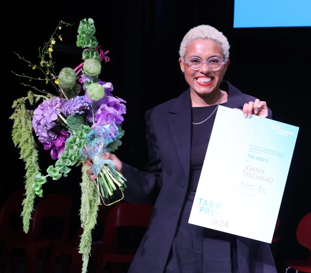 Joana Tischkau is holding flowers and the tabori certificate
